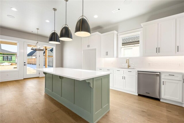 kitchen with a center island, stainless steel dishwasher, sink, white cabinetry, and hanging light fixtures