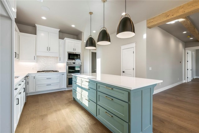 kitchen with wood finished floors, white cabinetry, stainless steel microwave, beamed ceiling, and backsplash