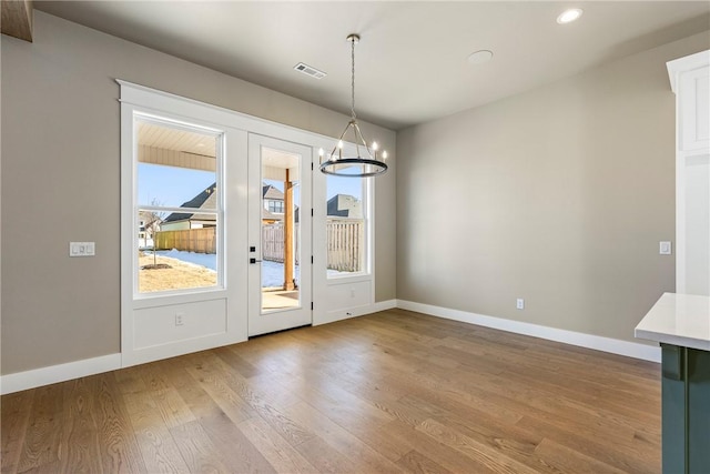 unfurnished dining area featuring wood-type flooring and an inviting chandelier