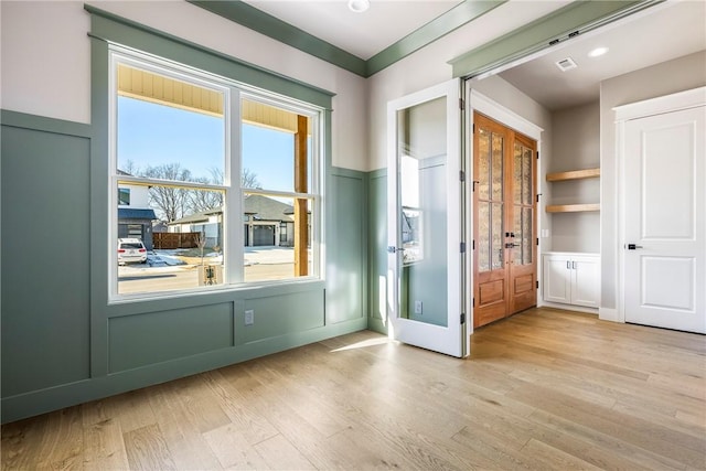 entryway with built in features, french doors, and light hardwood / wood-style flooring