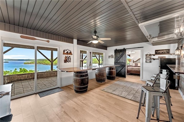 interior space with a water view, ceiling fan, and a barn door