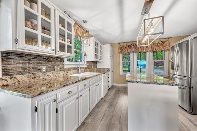 kitchen with white cabinetry, pendant lighting, stainless steel fridge, and sink