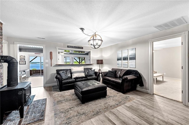 living room with a chandelier, light wood-type flooring, and a textured ceiling