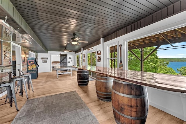 view of patio / terrace with a water view, a bar, and ceiling fan