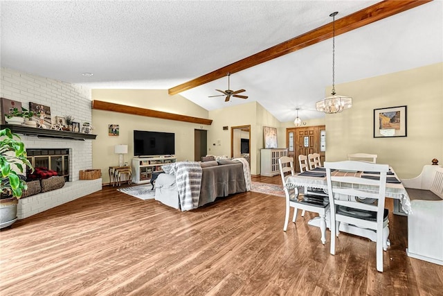 living room featuring vaulted ceiling with beams, hardwood / wood-style floors, a textured ceiling, and a fireplace