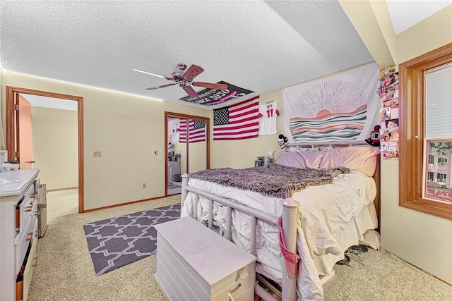 bedroom with ceiling fan, light carpet, a textured ceiling, and a closet