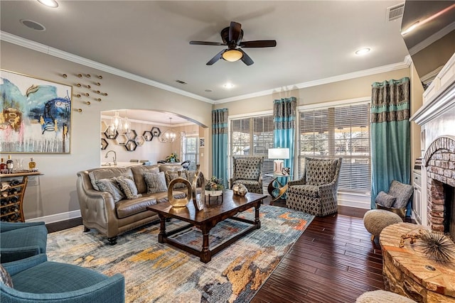 living room featuring ceiling fan with notable chandelier, dark wood-type flooring, and crown molding