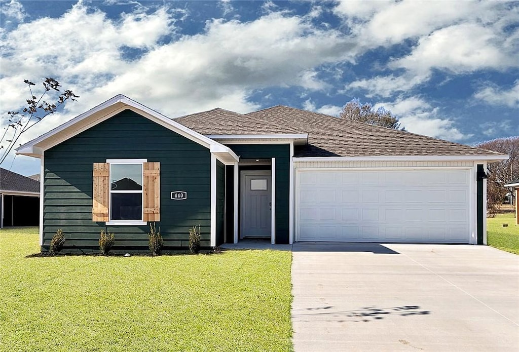 ranch-style house featuring a garage, driveway, a shingled roof, and a front lawn