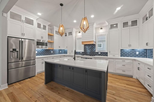 kitchen featuring pendant lighting, white cabinets, a center island with sink, and stainless steel appliances