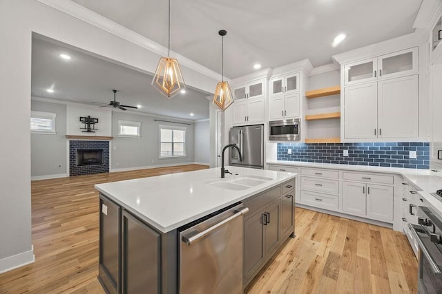 kitchen featuring white cabinetry, ceiling fan, stainless steel appliances, a kitchen island with sink, and sink