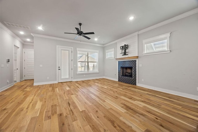 unfurnished living room with ceiling fan, a fireplace, crown molding, and light wood-type flooring