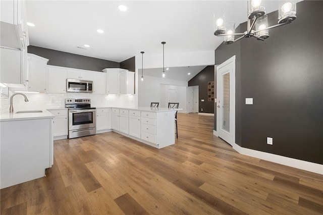 29 Shanklin Dr, Bella Vista, AR 72715 - kitchen with stainless steel appliances, vaulted ceiling, a peninsula, light wood-style flooring, and tasteful backsplash