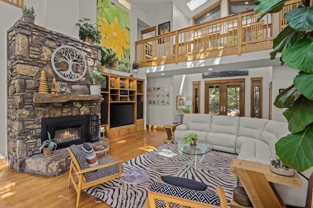 living room with high vaulted ceiling, wood-type flooring, french doors, and a fireplace