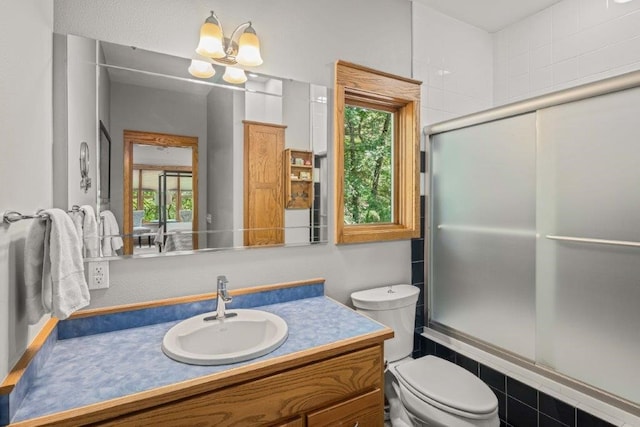 full bathroom featuring toilet, vanity, shower / bath combination with glass door, and an inviting chandelier