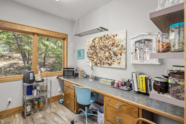 office with light hardwood / wood-style flooring and built in desk