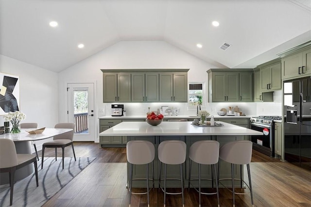 kitchen with a center island, black refrigerator with ice dispenser, dark wood-type flooring, stainless steel gas stove, and green cabinetry