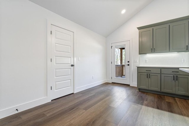 kitchen with dark wood-type flooring, lofted ceiling, and tasteful backsplash