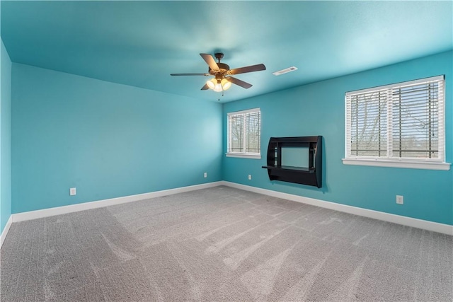 empty room with ceiling fan, plenty of natural light, and carpet floors