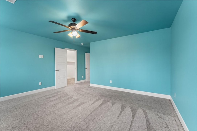 unfurnished bedroom with ceiling fan, a walk in closet, a closet, and carpet