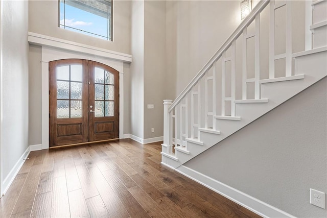 foyer with a towering ceiling, wood-type flooring, and french doors