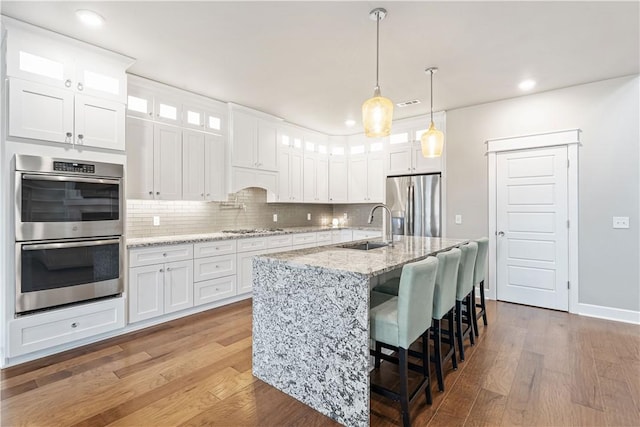 kitchen with stainless steel appliances, white cabinets, hanging light fixtures, and sink