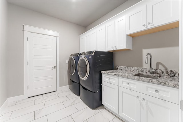 clothes washing area featuring washing machine and dryer, sink, and cabinets