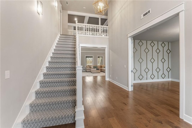 foyer with hardwood / wood-style floors, a towering ceiling, and an inviting chandelier