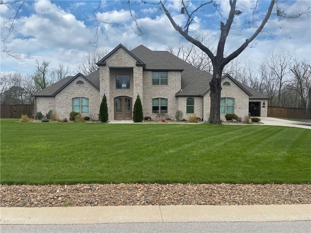 french provincial home with a front lawn and a garage