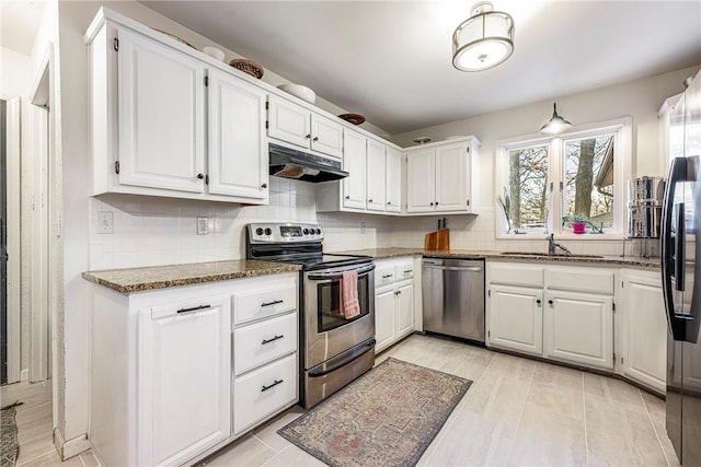 kitchen featuring tasteful backsplash, stainless steel appliances, white cabinetry, and dark stone counters