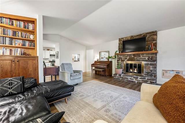 living room featuring lofted ceiling, a stone fireplace, and hardwood / wood-style floors