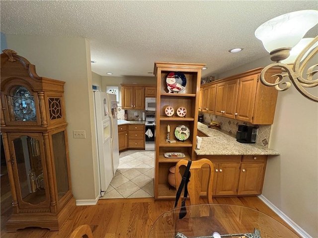 kitchen featuring range with electric cooktop, backsplash, light wood-type flooring, a textured ceiling, and white refrigerator with ice dispenser