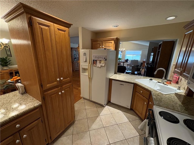 kitchen with a notable chandelier, sink, white appliances, light tile patterned flooring, and a textured ceiling