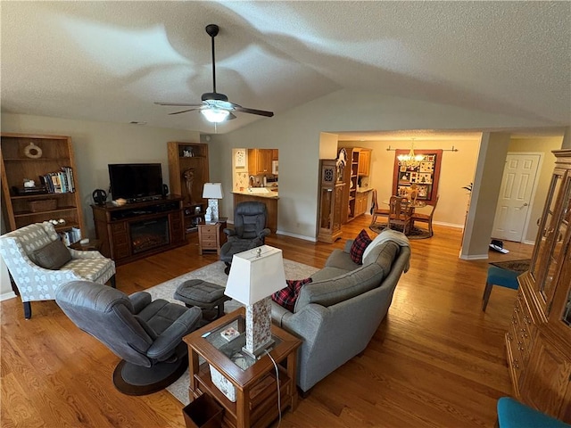 living room with lofted ceiling, ceiling fan with notable chandelier, a textured ceiling, and light hardwood / wood-style flooring