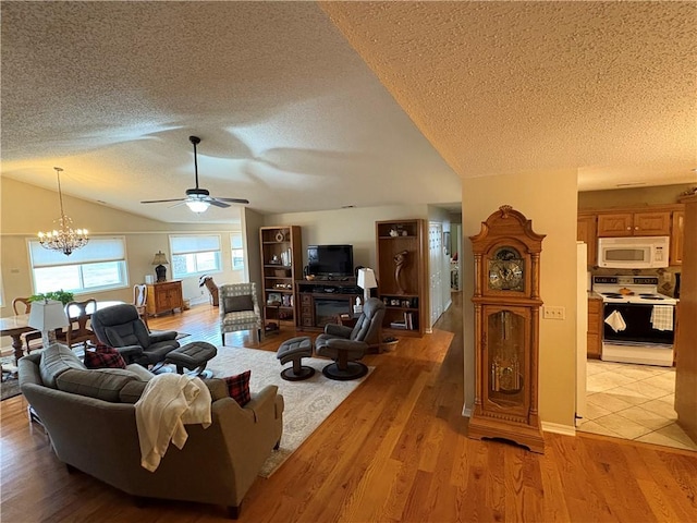 living room featuring light wood-type flooring, a textured ceiling, lofted ceiling, and ceiling fan with notable chandelier