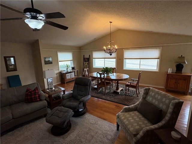 living room with vaulted ceiling, ceiling fan with notable chandelier, a textured ceiling, and hardwood / wood-style flooring