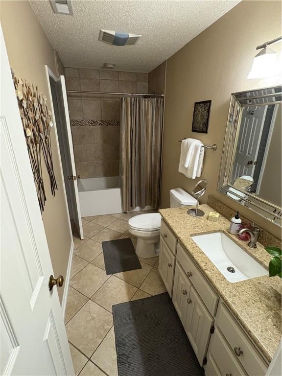 full bathroom with toilet, vanity, tile patterned flooring, shower / bath combination with curtain, and a textured ceiling