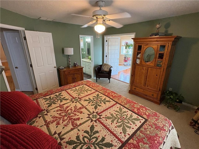 carpeted bedroom featuring ceiling fan, connected bathroom, and a textured ceiling