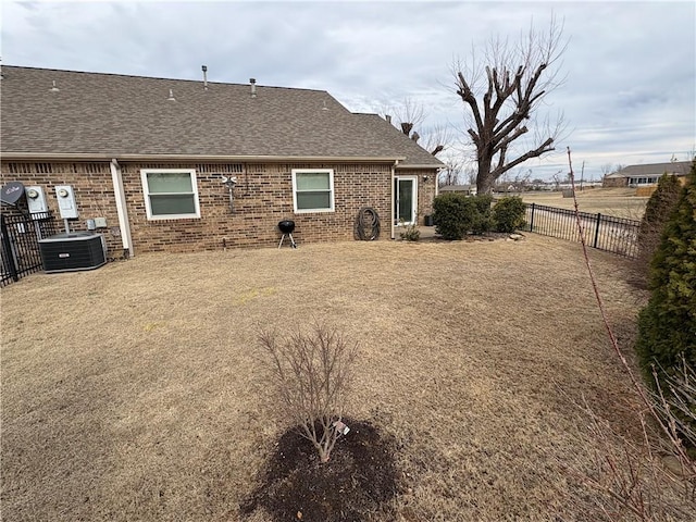 back of property featuring central air condition unit and a yard