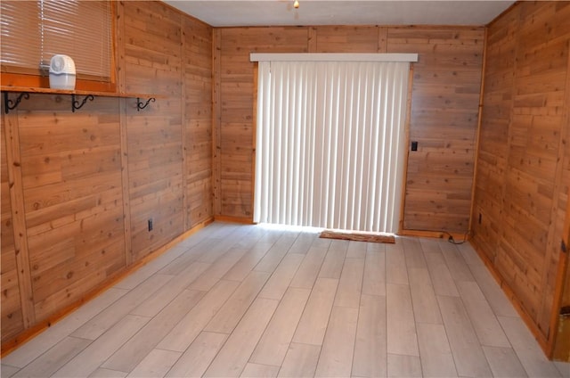 unfurnished room featuring light hardwood / wood-style floors and wood walls