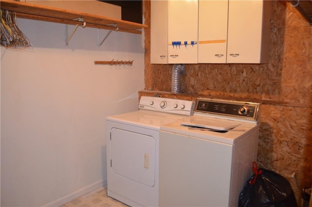 washroom featuring washing machine and dryer, baseboards, cabinet space, and light floors