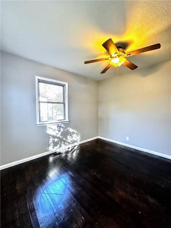 spare room with a textured ceiling, wood-type flooring, visible vents, and baseboards