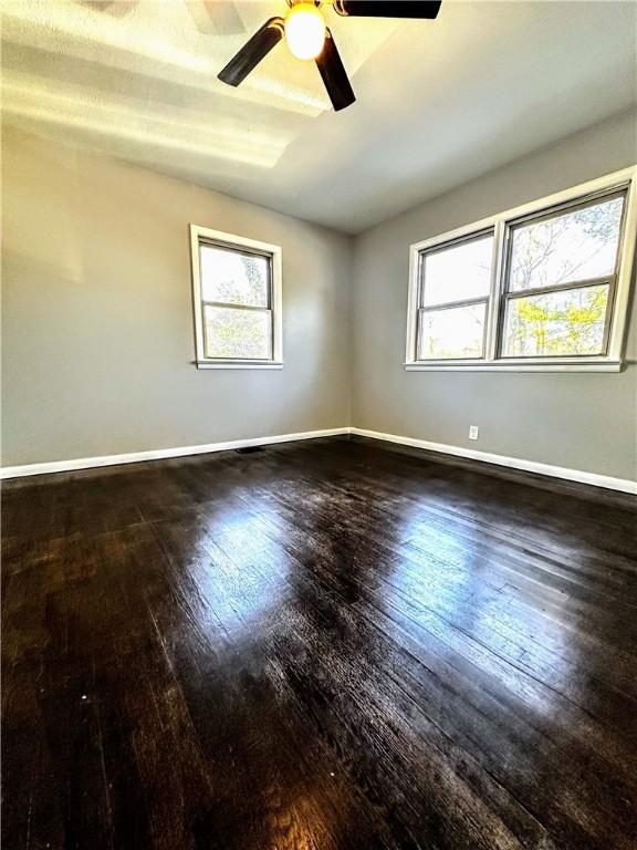 empty room with a wealth of natural light, baseboards, and hardwood / wood-style floors