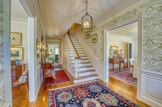 entryway featuring crown molding, a notable chandelier, and light wood-type flooring