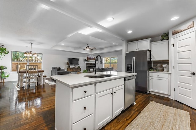 kitchen featuring ceiling fan with notable chandelier, white cabinets, appliances with stainless steel finishes, an island with sink, and sink