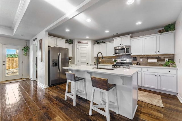 kitchen featuring white cabinetry, stainless steel appliances, a kitchen island with sink, dark hardwood / wood-style flooring, and sink