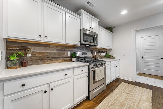 kitchen featuring dark wood-type flooring, white cabinets, stainless steel appliances, and tasteful backsplash