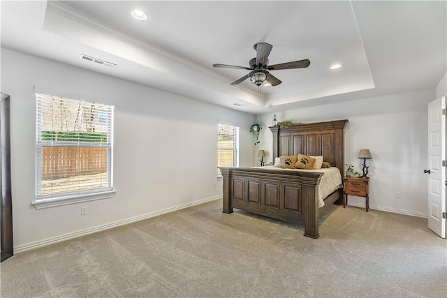 bedroom with ceiling fan, light colored carpet, a tray ceiling, and ornamental molding