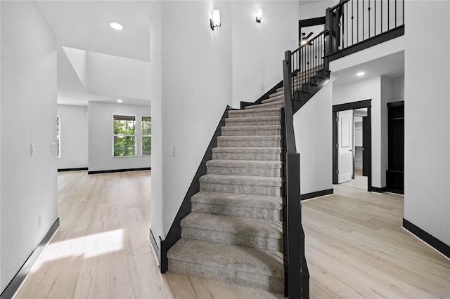 stairs with a towering ceiling and wood-type flooring