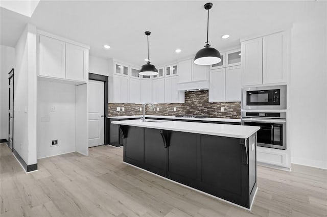 kitchen with sink, white cabinets, appliances with stainless steel finishes, and an island with sink