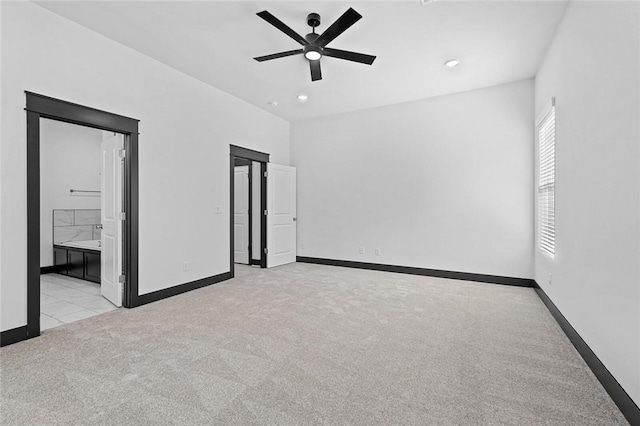 unfurnished bedroom featuring ceiling fan, light colored carpet, and ensuite bath